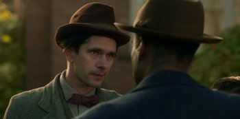 Movie still from “Fargo” (2014), created by Noah Hawley – A man wearing a hat and a bow tie talking to another man wearing a hat and a bow tie; Close Up shot, Over the shoulder angle