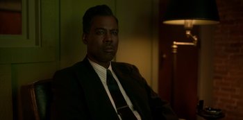 Movie still from “Fargo” (2014), created by Noah Hawley – A man wearing a suit and tie sitting in a chair; Close Up shot, Over the shoulder angle
