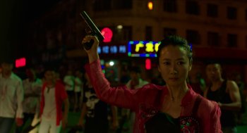 A woman holding a gun up in the air in front of a crowd of onlookers at night