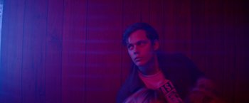 Movie still from “Assassination Nation” (2018), directed by Sam Levinson – A young man is standing in a purple room; Close Up shot, Low angle