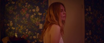 Movie still from “Assassination Nation” (2018), directed by Sam Levinson – A woman standing in a room with long red hair; Medium shot, Over the shoulder angle