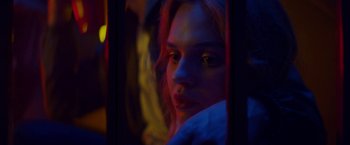 Movie still from “Assassination Nation” (2018), directed by Sam Levinson – A woman with red hair looking out of a window; Close Up shot, Low angle