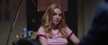 Movie still from “Assassination Nation” (2018), directed by Sam Levinson – A woman with long red hair sitting in a room; Medium shot, Over the shoulder angle