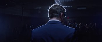 Movie still from “Assassination Nation” (2018), directed by Sam Levinson – A person wearing a suit; Medium shot, Low angle