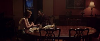 Movie still from “Assassination Nation” (2018), directed by Sam Levinson – Two people sitting at a dinner table with wine glasses; Medium shot, Over the shoulder angle