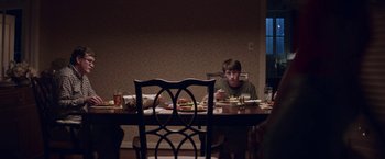 Movie still from “Assassination Nation” (2018), directed by Sam Levinson – A boy sitting at a dinner table eating a sandwich; Medium shot, Over the shoulder angle