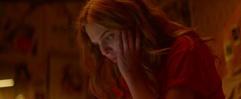 Movie still from “Assassination Nation” (2018), directed by Sam Levinson – A beautiful young woman with long red hair and wearing a red shirt; Close Up shot, Low angle
