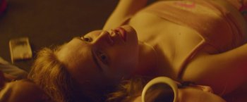 Movie still from “Assassination Nation” (2018), directed by Sam Levinson – A woman laying on the ground with a cup in her hand; Close Up shot, High angle