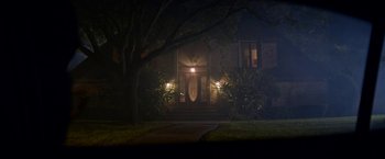Movie still from “Assassination Nation” (2018), directed by Sam Levinson – A house with lights on the front of the house at night time; Extreme Wide shot, High angle