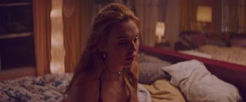 Movie still from “Assassination Nation” (2018), directed by Sam Levinson – A woman sitting on top of a bed in front of a window; Close Up shot, Over the shoulder angle