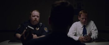 Movie still from “Assassination Nation” (2018), directed by Sam Levinson – A police officer sitting in front of two other people; Medium shot, Over the shoulder angle