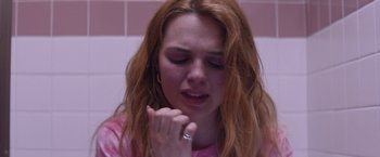 Movie still from “Assassination Nation” (2018), directed by Sam Levinson – A woman with long red hair is sitting in a bathroom; Close Up shot, Over the shoulder angle