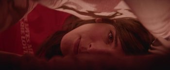 Movie still from “Assassination Nation” (2018), directed by Sam Levinson – A woman's face as she lays on a bed; Extreme Close Up shot, Overhead angle