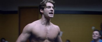 Movie still from “Assassination Nation” (2018), directed by Sam Levinson – A man with no shirt standing in front of a wall; Close Up shot, Low angle