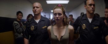 Movie still from “Assassination Nation” (2018), directed by Sam Levinson – A woman standing next to a man in a room; Medium shot, Over the shoulder angle