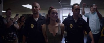 Movie still from “Assassination Nation” (2018), directed by Sam Levinson – A woman is being held by two police officers; Medium shot, Over the shoulder angle