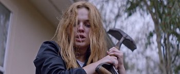 Movie still from “Assassination Nation” (2018), directed by Sam Levinson – A woman with long hair holding a hammer; Close Up shot, Low angle