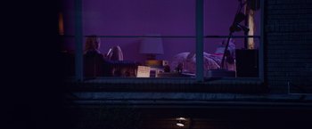 Movie still from “Assassination Nation” (2018), directed by Sam Levinson – A woman sitting on a chair in a room; Wide shot, Low angle