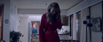 Movie still from “Assassination Nation” (2018), directed by Sam Levinson – A woman in a red coat talking on a phone; Medium shot, Over the shoulder angle