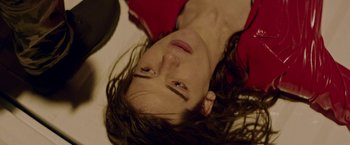 Movie still from “Assassination Nation” (2018), directed by Sam Levinson – A woman laying on the ground with her eyes closed; Close Up shot, Overhead angle