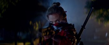 Movie still from “Assassination Nation” (2018), directed by Sam Levinson – A woman in a red jacket is holding a gun; Medium shot, Low angle