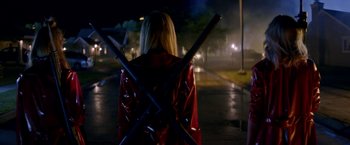 Movie still from “Assassination Nation” (2018), directed by Sam Levinson – A woman in a red jacket holding a pair of poles; Wide shot, Over the shoulder angle