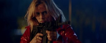 Movie still from “Assassination Nation” (2018), directed by Sam Levinson – A woman in a red jacket is holding a gun; Close Up shot, Over the shoulder angle