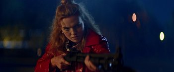 Movie still from “Assassination Nation” (2018), directed by Sam Levinson – A woman in a red jacket is holding a gun; Medium shot, Over the shoulder angle