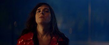 Movie still from “Assassination Nation” (2018), directed by Sam Levinson – A woman with long black hair is looking up; Close Up shot, Over the shoulder angle