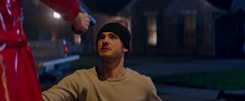 Movie still from “Assassination Nation” (2018), directed by Sam Levinson – A man in a black hat is holding a gun in his hand; Close Up shot, Over the shoulder angle