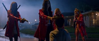 Movie still from “Assassination Nation” (2018), directed by Sam Levinson – A woman in a red jacket is handing a man a piece of paper; Medium shot, Over the shoulder angle