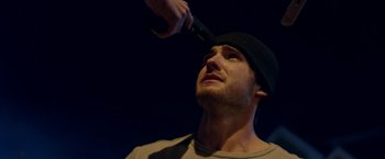 Movie still from “Assassination Nation” (2018), directed by Sam Levinson – A man with a hat on his head is holding a blow dryer in his hand; Close Up shot, Low angle