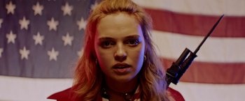 Movie still from “Assassination Nation” (2018), directed by Sam Levinson – A person with a flag in the background; Close Up shot, Low angle