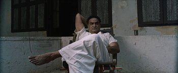 A man sitting in a chair with his arm resting on a pillow