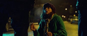Movie still from “Attack the Block” (2011), directed by Joe Cornish – A woman in a green coat is smoking a cigarette; Medium shot, High angle