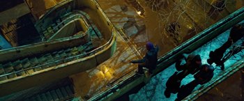 Movie still from “Attack the Block” (2011), directed by Joe Cornish – A person standing on a railing in the middle of the night; Extreme Wide shot, Overhead angle