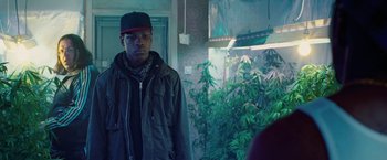 Movie still from “Attack the Block” (2011), directed by Joe Cornish – A man standing in front of a wall with marijuana plants; Medium shot, Over the shoulder angle