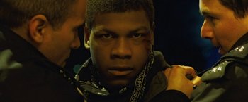 Movie still from “Attack the Block” (2011), directed by Joe Cornish – A young man with bandages on his face; Close Up shot, Over the shoulder angle