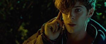 Movie still from “Attack the Block” (2011), directed by Joe Cornish – A young man talking on a cell phone while sitting down; Close Up shot, Low angle
