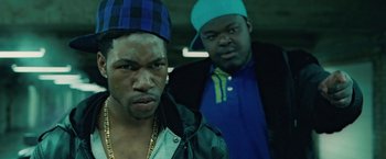 Movie still from “Attack the Block” (2011), directed by Joe Cornish – Two men standing next to each other in a parking lot; Close Up shot, Over the shoulder angle