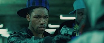 Movie still from “Attack the Block” (2011), directed by Joe Cornish – A person holding a gun in a room; Close Up shot, Over the shoulder angle