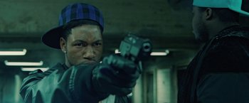 Movie still from “Attack the Block” (2011), directed by Joe Cornish – A man holding a gun while wearing a hat; Close Up shot, Overhead angle