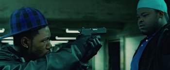 Movie still from “Attack the Block” (2011), directed by Joe Cornish – A person holding a gun in a room; Close Up shot, Low angle