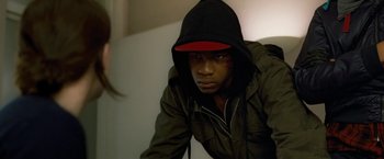 Movie still from “Attack the Block” (2011), directed by Joe Cornish – A young man wearing a black hooded jacket and a red hat; Close Up shot, Low angle