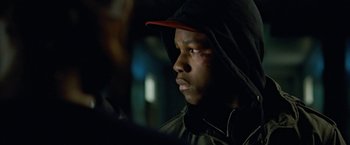 Movie still from “Attack the Block” (2011), directed by Joe Cornish – A young man wearing a black jacket and a red hat; Close Up shot, Over the shoulder angle