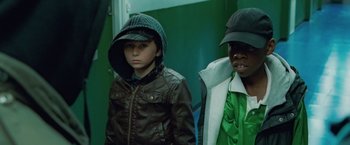 Movie still from “Attack the Block” (2011), directed by Joe Cornish – Two young boys wearing jackets and hats standing next to each other; Close Up shot, High angle