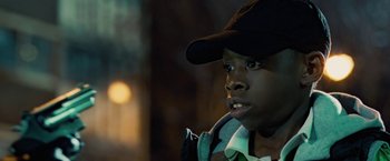 Movie still from “Attack the Block” (2011), directed by Joe Cornish – A young boy wearing a baseball cap and a backpack; Close Up shot, High angle