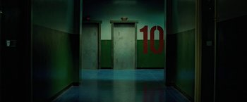 Movie still from “Attack the Block” (2011), directed by Joe Cornish – Three elevators in an empty room with the number 1 0 painted on them; Wide shot, Overhead angle