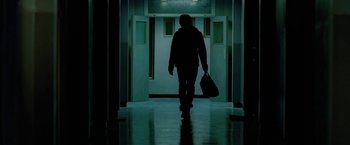 Movie still from “Attack the Block” (2011), directed by Joe Cornish – A person walking down a hall way with a bag; Wide shot, Low angle