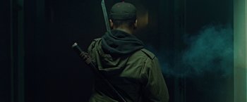 Movie still from “Attack the Block” (2011), directed by Joe Cornish – A man in a green jacket holding a sword in a dark room; Medium shot, Low angle